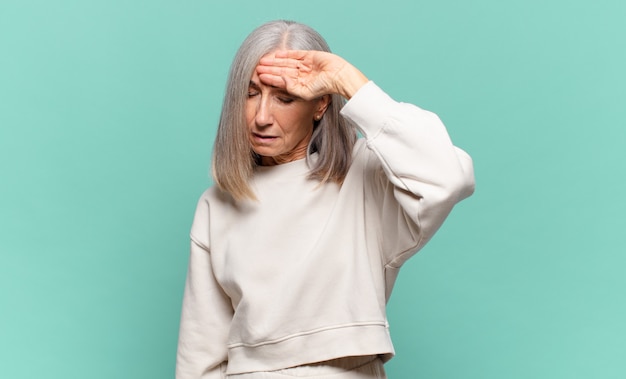 Middle age woman looking stressed, tired and frustrated, drying sweat off forehead, feeling hopeless and exhausted