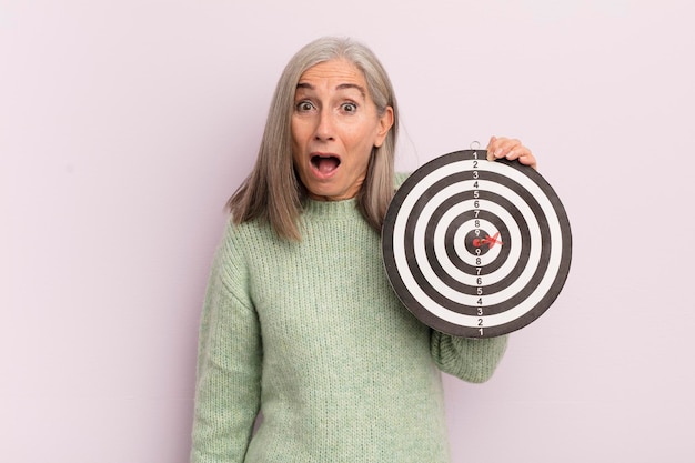 Middle age woman looking very shocked or surprised darts target concept