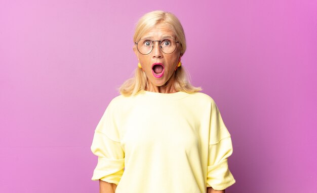 Middle age woman looking very shocked or surprised, staring with open mouth saying wow