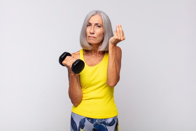 Middle age woman making capice or money gesture, telling you to pay your debts!. fitness concept