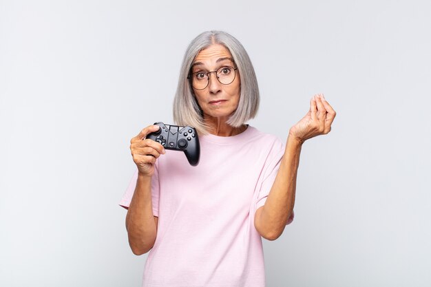 Middle age woman making capice or money gesture, telling you to pay your debts!. playing console concept