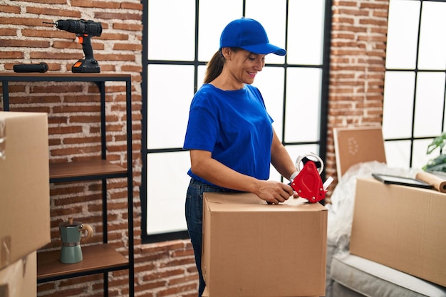 Женщина средних лет перевозит работника, упаковывающего картонную коробку в новый дом