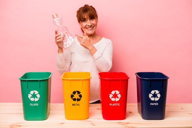 Middle age woman recycling isolated on pink background