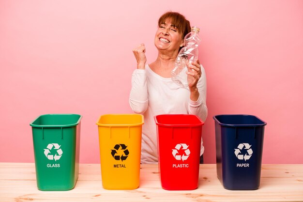 Middle age woman recycling isolated on pink background