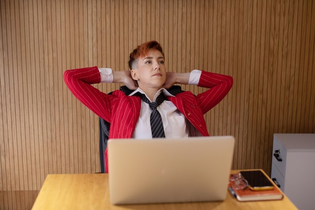 Middle age woman in red suit smiling confident relaxing at office