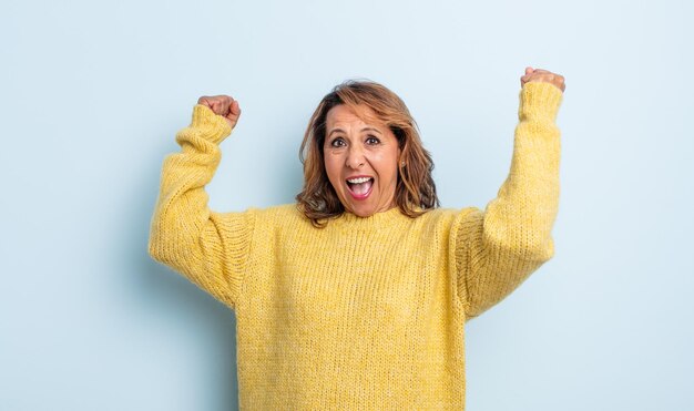 Middle age woman shouting triumphantly, looking like excited, happy and surprised winner, celebrating