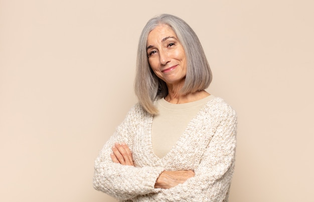 Middle age woman smiling to camera with crossed arms and a happy, confident, satisfied expression, lateral view