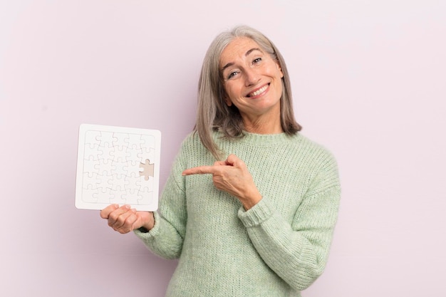 Middle age woman smiling cheerfully feeling happy and pointing to the side puzzle challenge concept