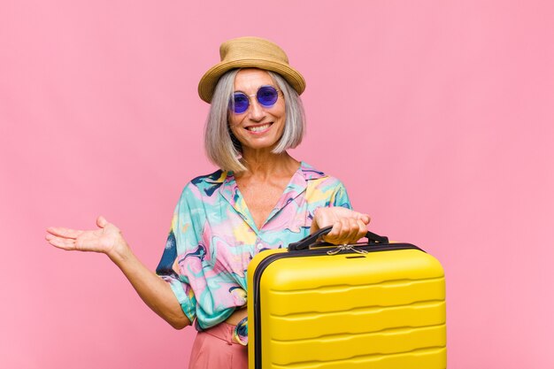 Middle age woman smiling cheerfully, feeling happy and showing a concept in copy space with palm of hand