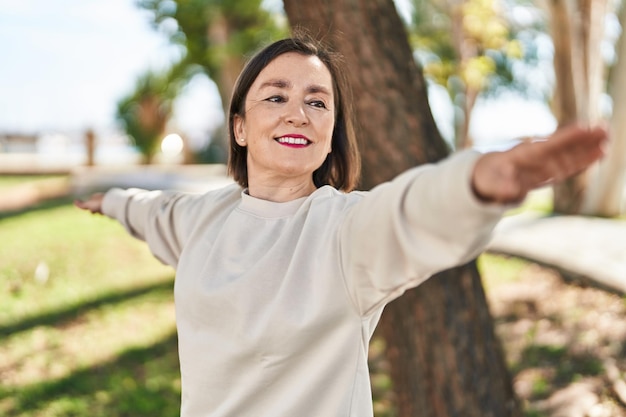 Middle age woman smiling confident training yoga at park