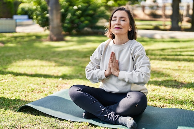 Middle age woman smiling confident training yoga at park