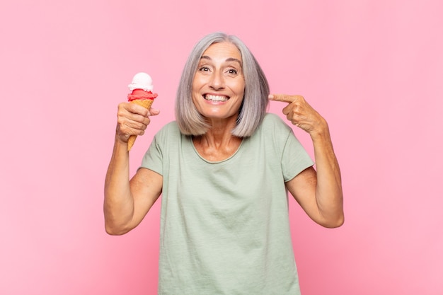 Middle age woman smiling confidently pointing to own broad smile, positive, relaxed, satisfied attitude
