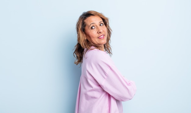 Middle age woman smiling gleefully, feeling happy, satisfied and relaxed, with crossed arms and looking to the side