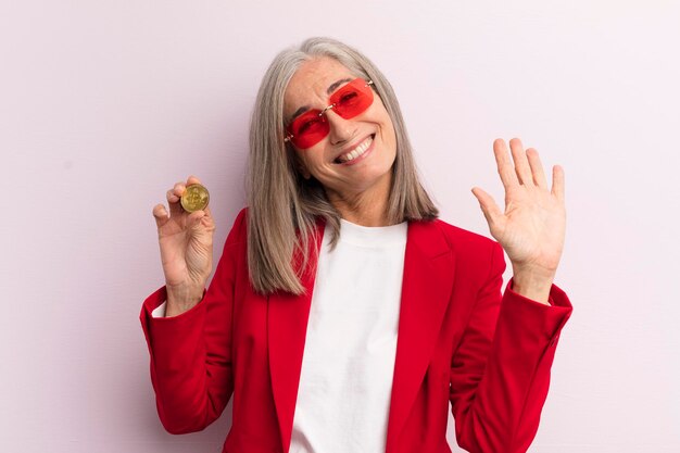 Middle age woman smiling happily waving hand welcoming and greeting you bitcoin concept