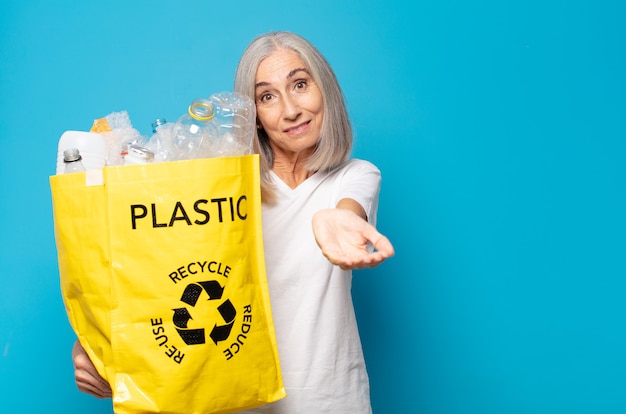 Middle age woman smiling happily with friendly, confident holding a recycle bag