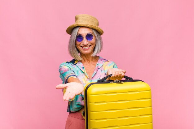 Middle age woman smiling happily with friendly, confident, positive look, offering and showing an object or concept