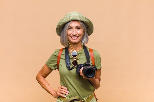 Middle age woman smiling happily with a hand on hip and confident, positive, proud and friendly attitude