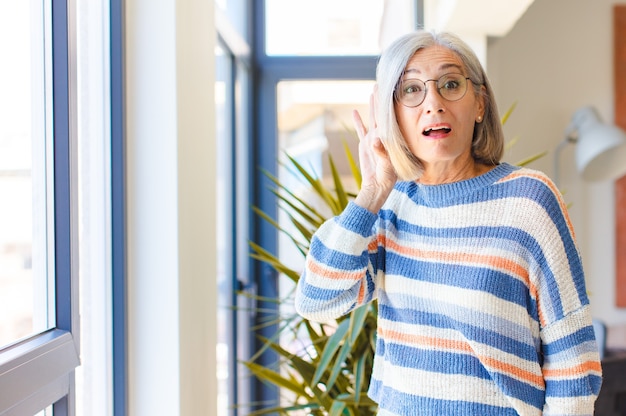 Middle age woman smiling, looking curiously to the side, trying to listen to gossip or overhearing a secret