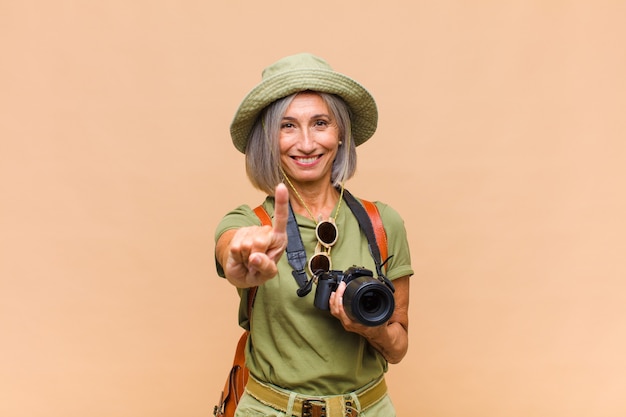 Middle age woman smiling and looking friendly, showing number one or first with hand forward, counting down