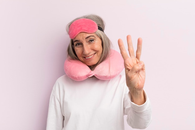 Middle age woman smiling and looking friendly showing number three flight passenger concept