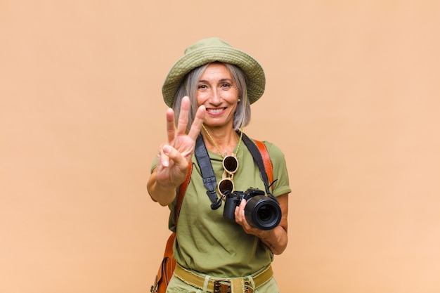 Middle age woman smiling and looking friendly, showing number three or third with hand forward, counting down