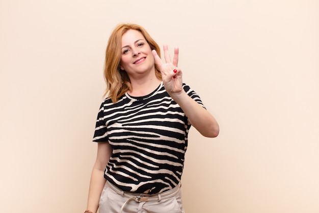 Middle age woman smiling and looking friendly, showing number three or third with hand forward, counting down