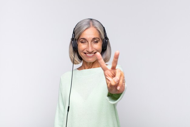 Middle age woman smiling and looking friendly, showing number two or second with hand forward