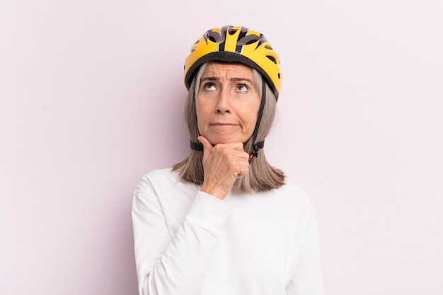 Middle age woman thinking feeling doubtful and confused bike helmet concept