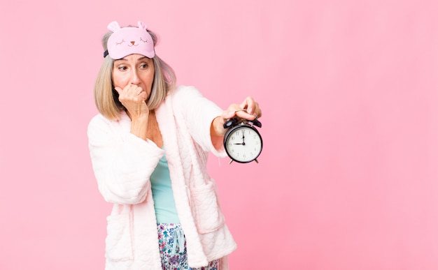 Middle age woman wearing night suit with an alarm clock