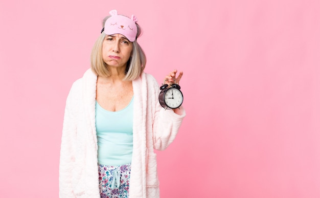 Middle age woman wearing night suit with an alarm clock