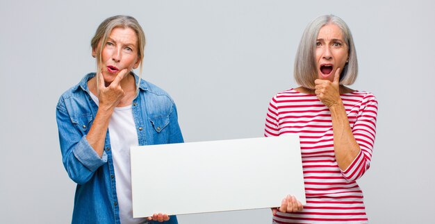 Middle age woman with mouth and eyes wide open and hand on chin, feeling unpleasantly shocked