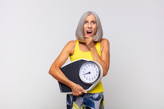 Middle age woman with mouth and eyes wide open and hand on chin isolated