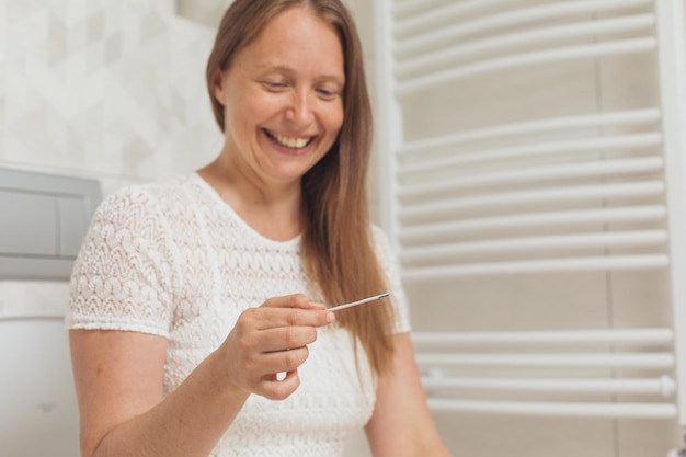 Middle age woman with pregnancy test in restroom