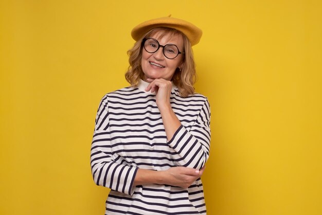 Middle age woman in yellow hat and glasses smiling looking at the camera