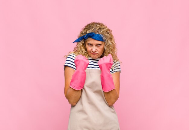 Photo middle age womanlooking confident, angry, strong and aggressive, with fists ready to fight in boxing position housekeeper concept