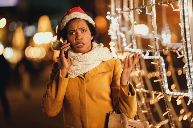 Middle age worried african woman talking on her smartphone on the christmas market in the city