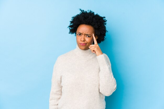 Middle aged african american woman against a blue wall isolated showing a disappointment gesture with forefinger.