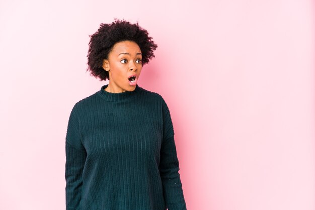 Middle aged african american woman against a pink isolated being shocked because of something she has seen.