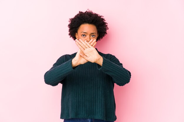 Middle aged african american woman against a pink  isolated doing a denial gesture