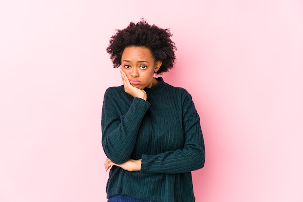 middle aged african american woman against a pink isolated who is bored, fatigued and need a relax day.