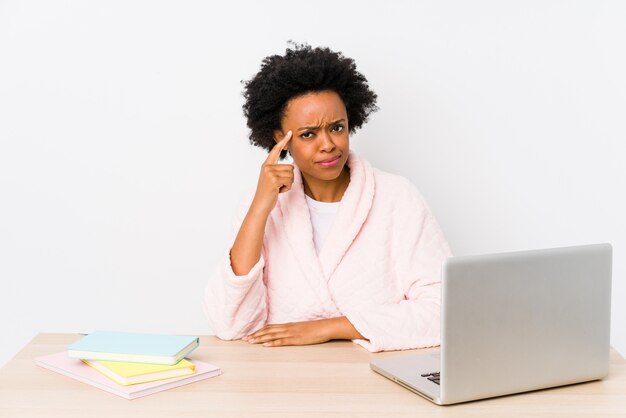 Middle aged african american woman working at home pointing temple with finger, thinking, focused on a task.