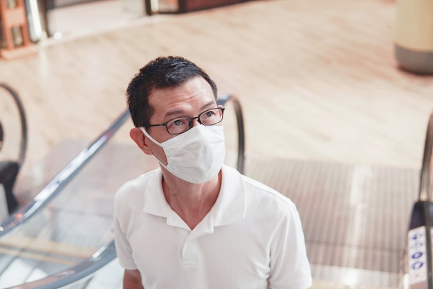 Middle aged asian man wearing glasses and medical face mask,\
wuhan coronavirus outbreak, air pollution and health concept