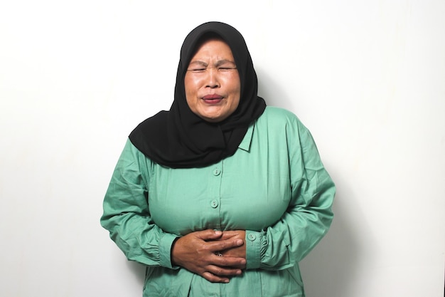 ヒジャブを身に着けている中年のアジア人女性は、急性腹痛に苦しんでとても気分が悪い