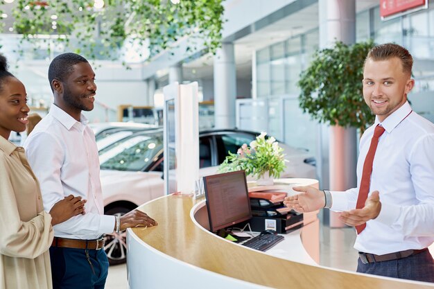 Middle-aged beautiful married couple entered modern dealership