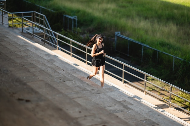 Middle-aged beautiful sport asian woman outdoor runner athlete\
running on stadium stairs active and healthy lifestyle.