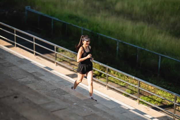 Middle-aged beautiful sport asian woman outdoor runner athlete\
running on stadium stairs active and healthy lifestyle.