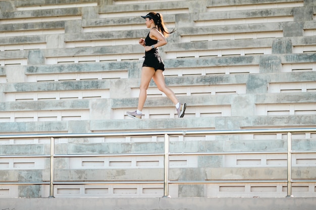 Middle-aged beautiful sport asian woman outdoor runner athlete\
running on stadium stairs active and healthy lifestyle.