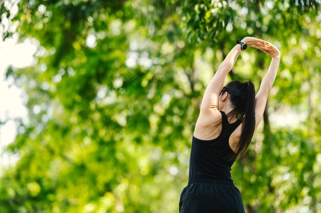 Foto bella donna asiatica sportiva di mezza età che allunga le braccia e guarda lontano prima della sessione di allenamento fitness al parco