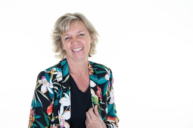 Middle aged blond woman with blonde curly hair in floral fashion vest with blue eyes on white background