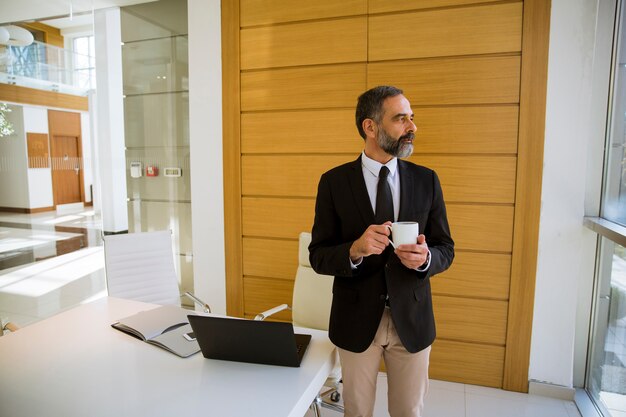 middle aged businessman holding cup of coffee or in the office